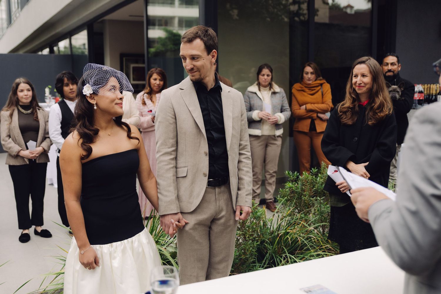 Couple holds hands at outdoor wedding ceremony with guests watching.