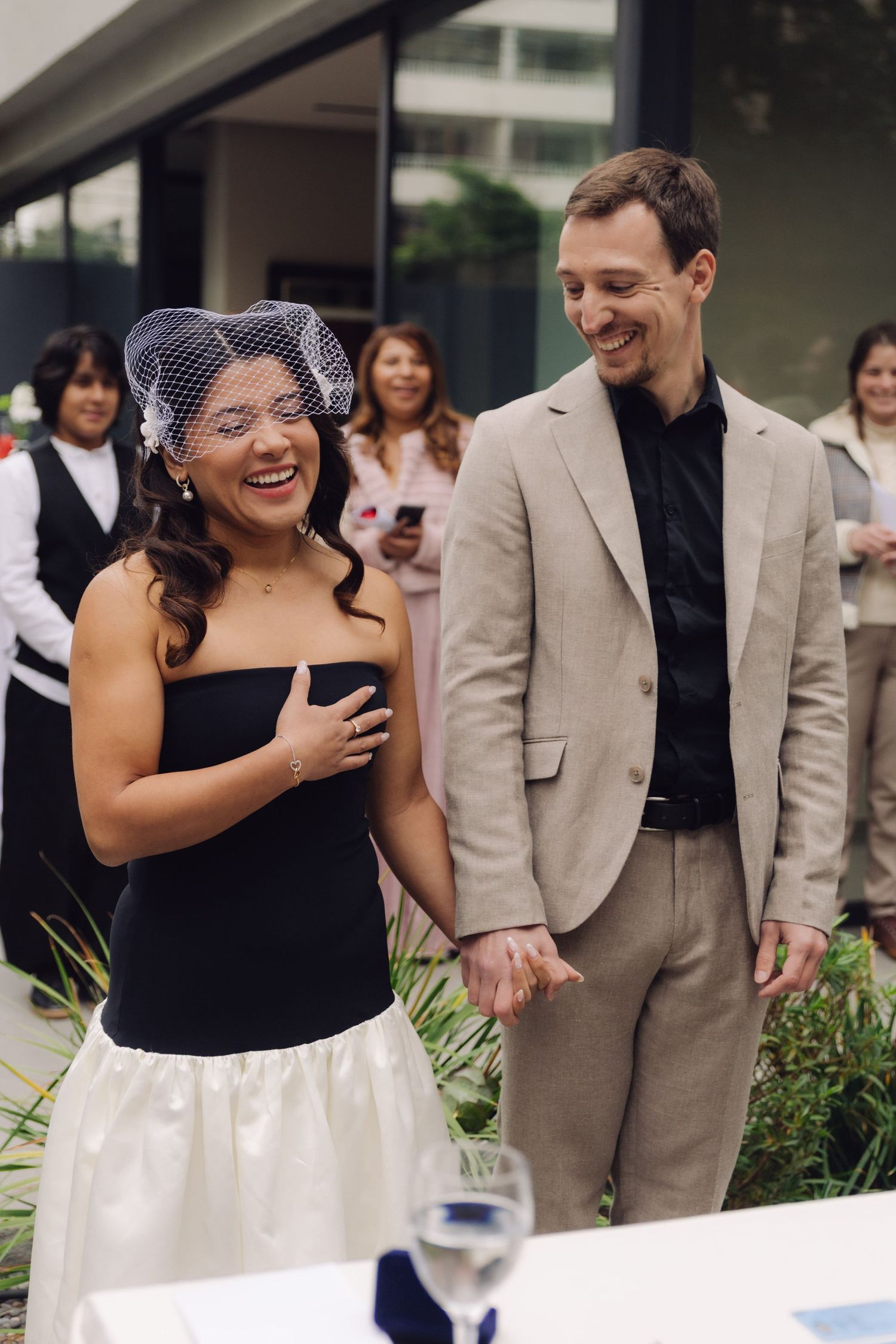 Bride and groom smile while holding hands at outdoor wedding ceremony.