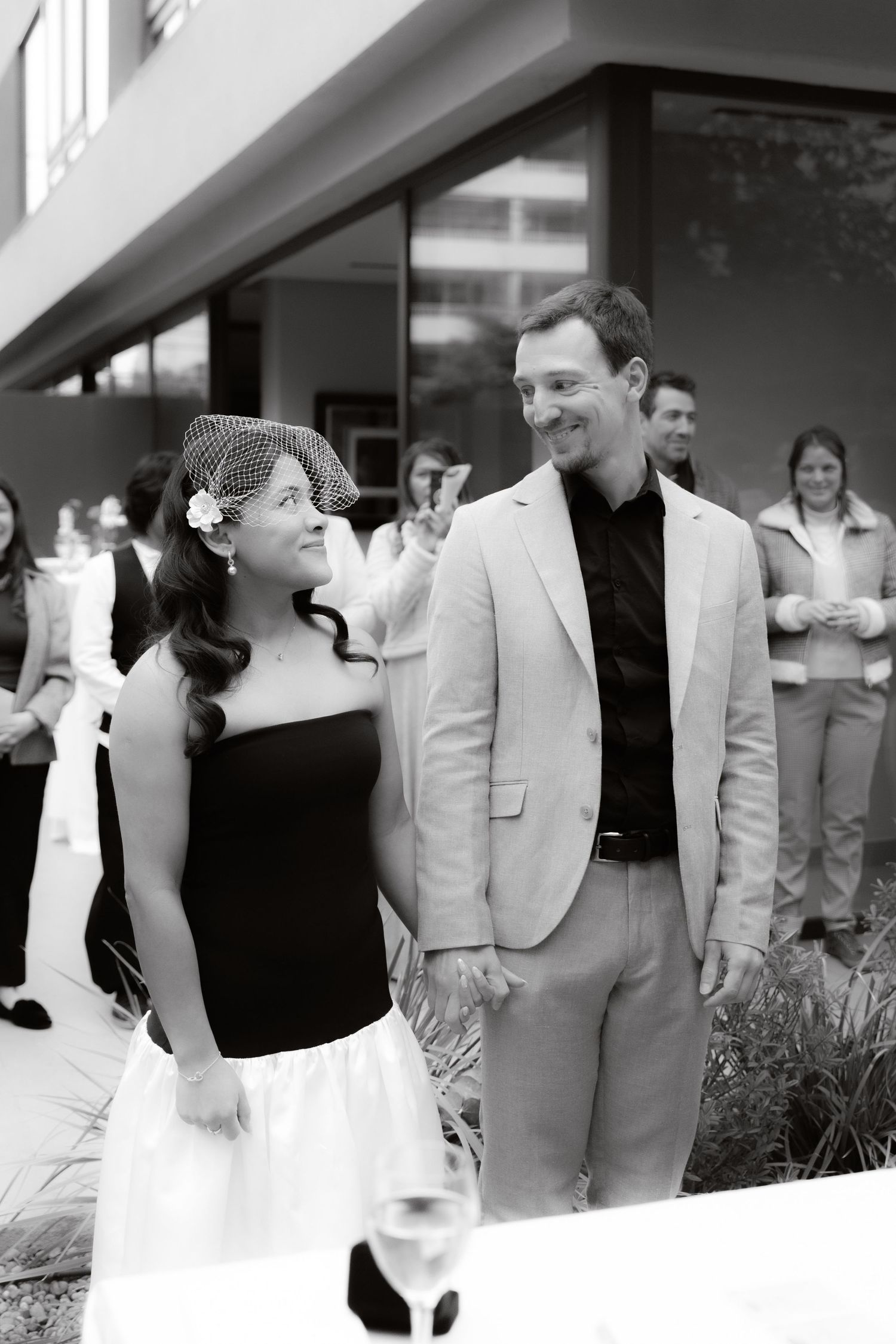Groom places wedding ring on bride's finger during outdoor ceremony.