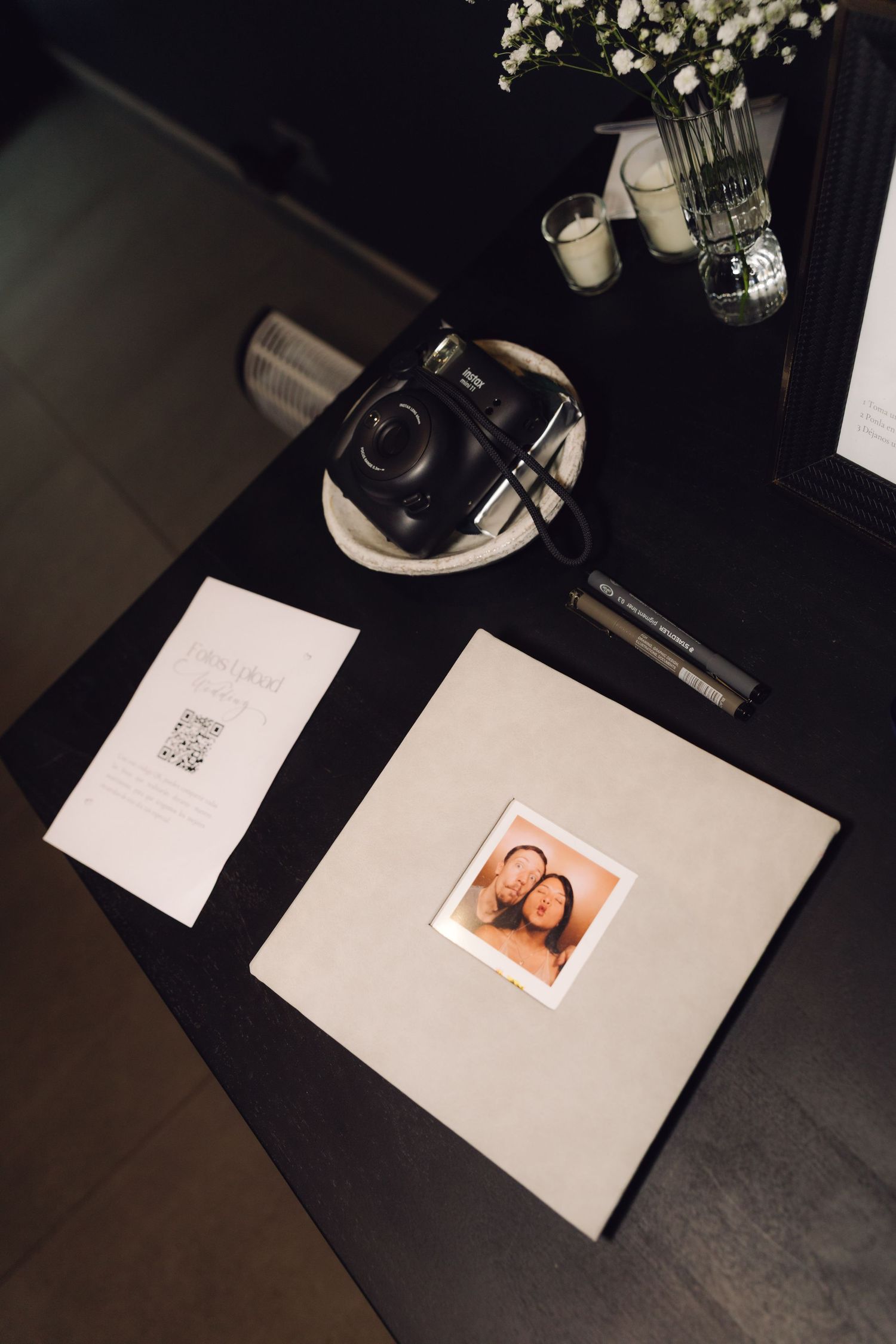 Wedding guest book table with Instax camera, polaroid photo, candles and white flowers.