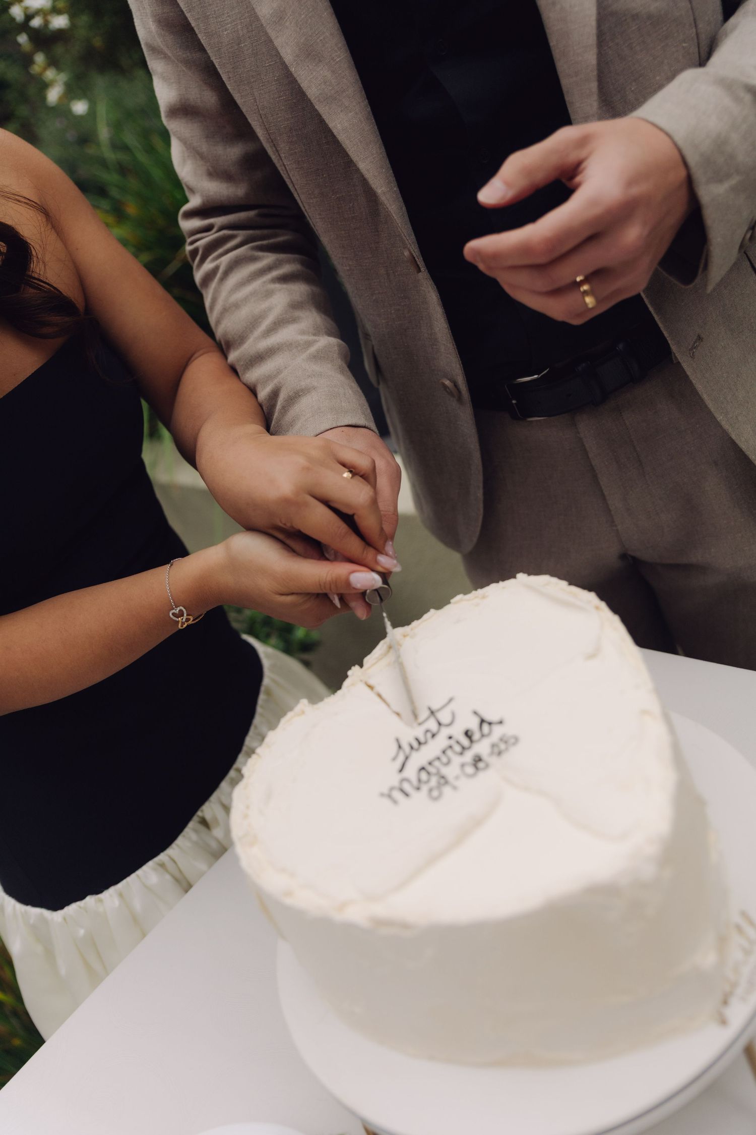 Close-up of couple cutting heart-shaped Just Married wedding cake together.