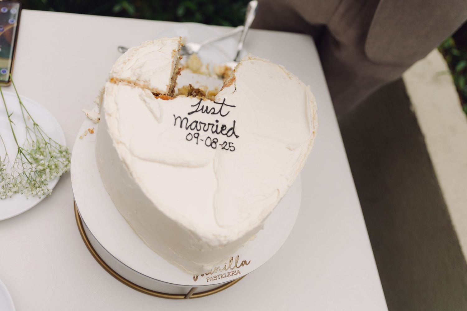 Heart-shaped Just Married wedding cake dated 09.08.25 with gold detail on white stand.