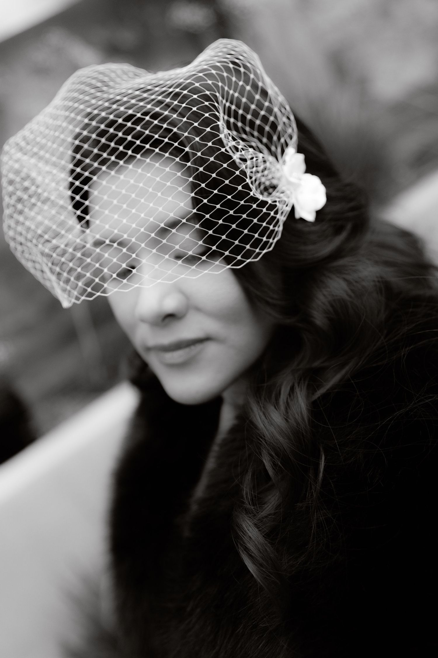 Black and white portrait of bride wearing elegant birdcage veil with floral detail.