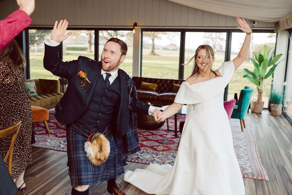 Wedding guests dance and celebrate together on a dance floor during a lively reception party.