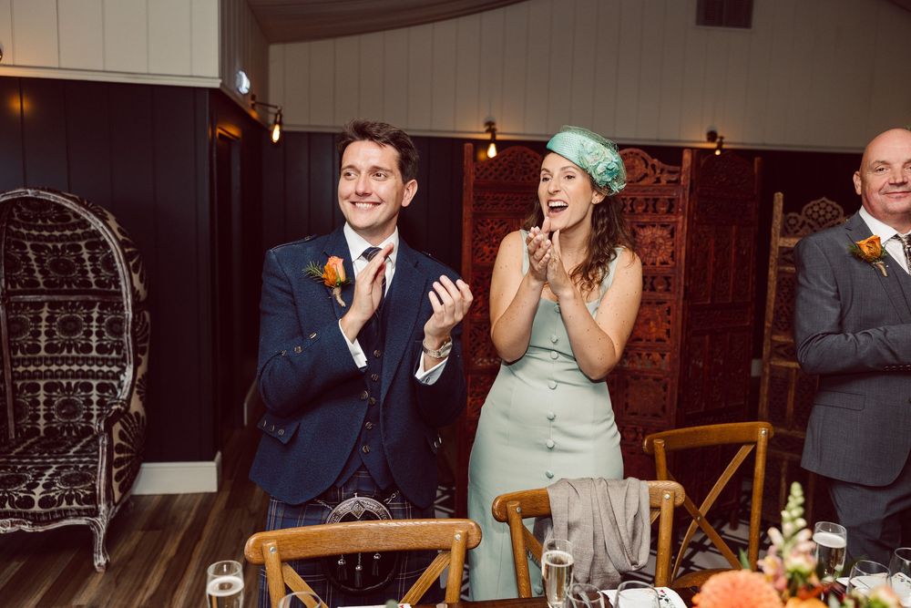 Candid moments of celebration and laughter at a rustic wedding reception venue with string lights and wooden decor.