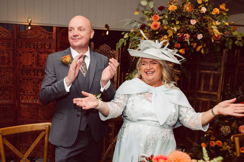 Couple shares a joyful dance moment at their wedding reception with autumn floral decorations in the background.