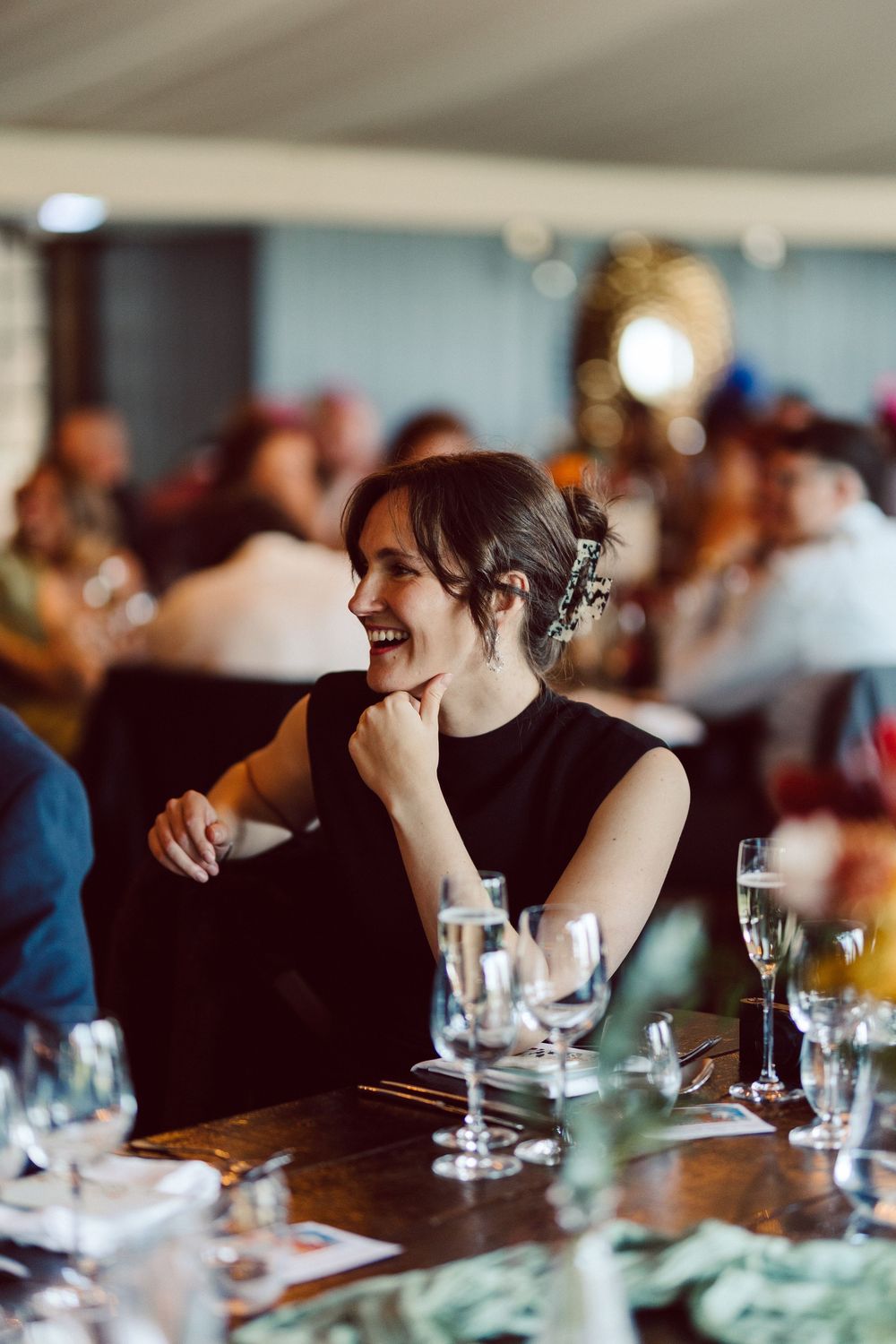Guests engaged in lively conversation at an elegant dinner party with wine glasses and table settings.