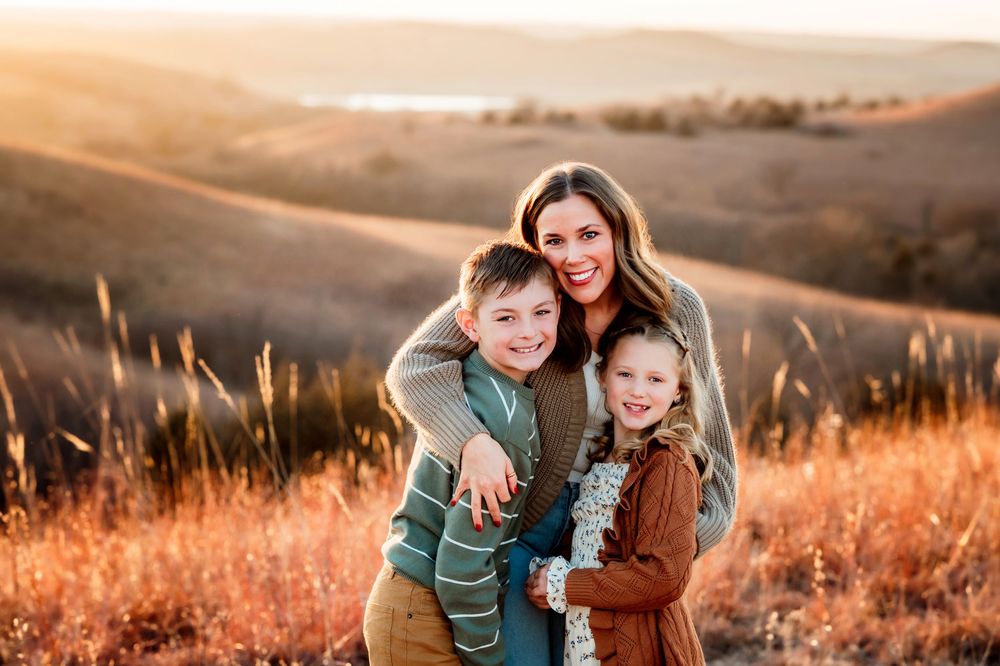A mother and daughter share tender moments in a golden field at sunset during a family photo session.