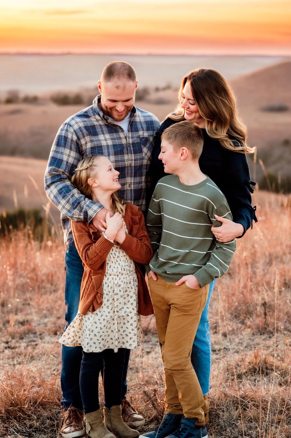 Family sharing joyful moments together during golden hour sunset in a field with tall grass.