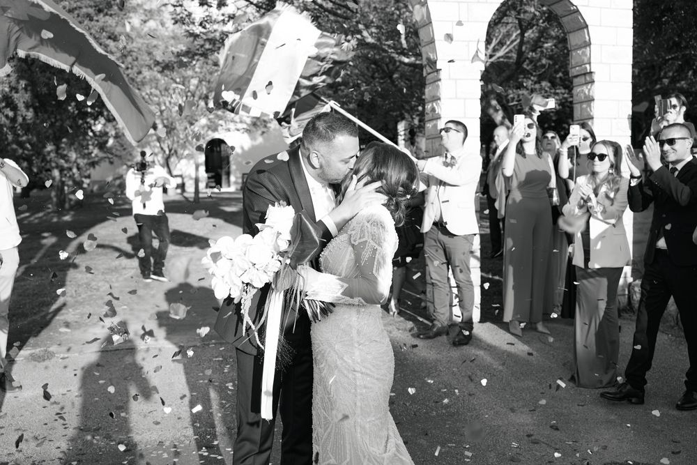 Wedding guests celebrate by throwing confetti during an outdoor celebration.