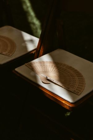 Decorative paper fans cast dramatic shadows on white surfaces in moody lighting.