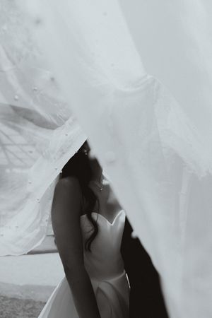 Artistic black and white photo of flowing white wedding dress fabric creating dramatic shadows.