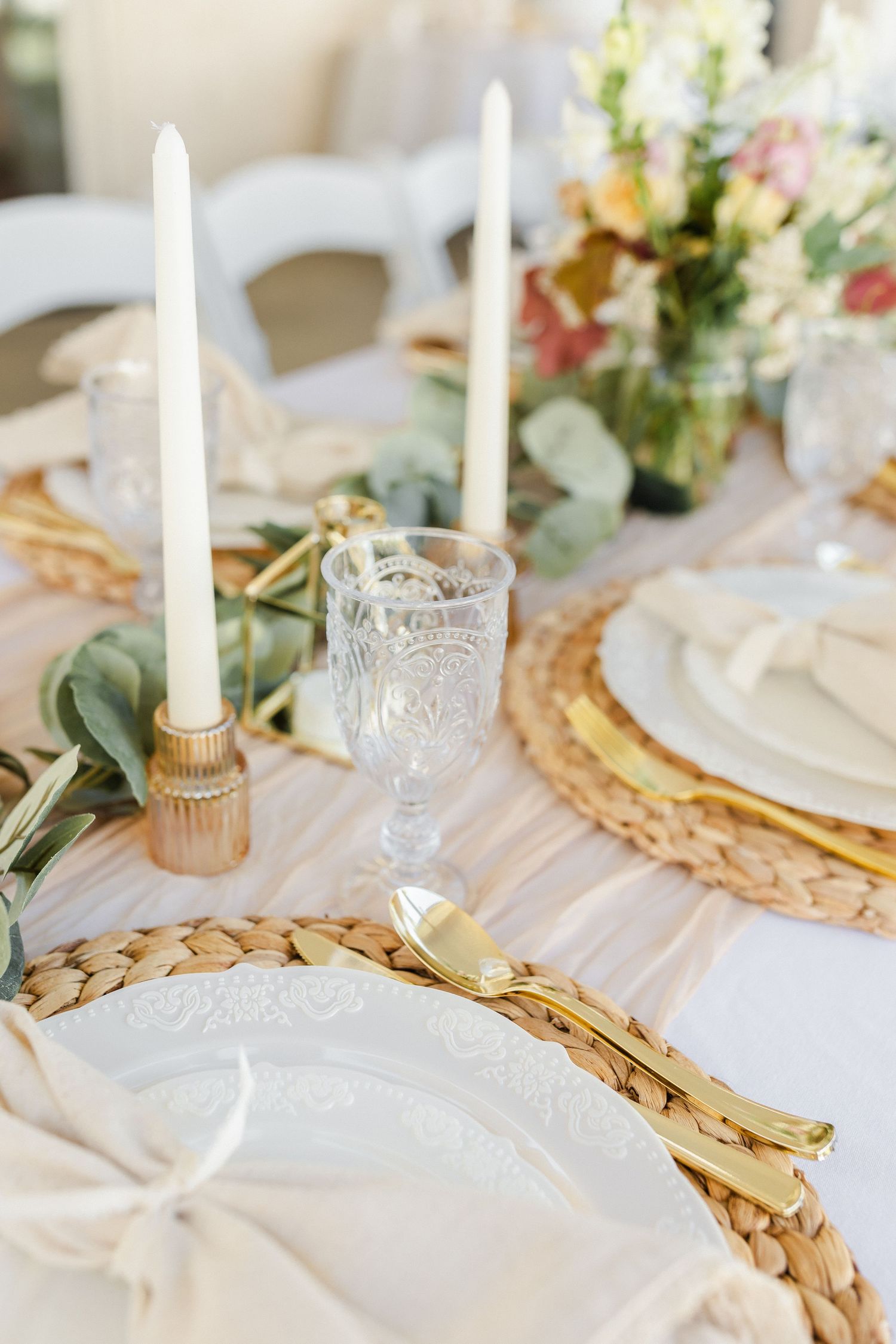 Elegant table setting with candles in glass holders on woven placemats with delicate floral arrangements captured by Chelsee Rawe Photo