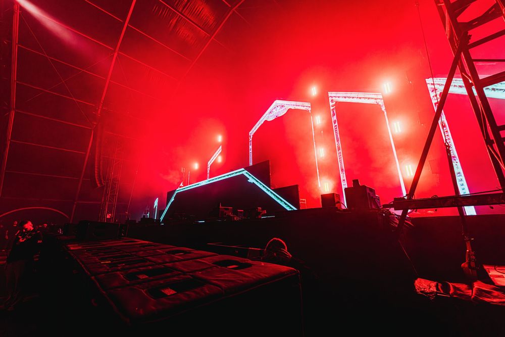 Concert stage illuminated with dramatic red lighting and fog effects during a live performance.