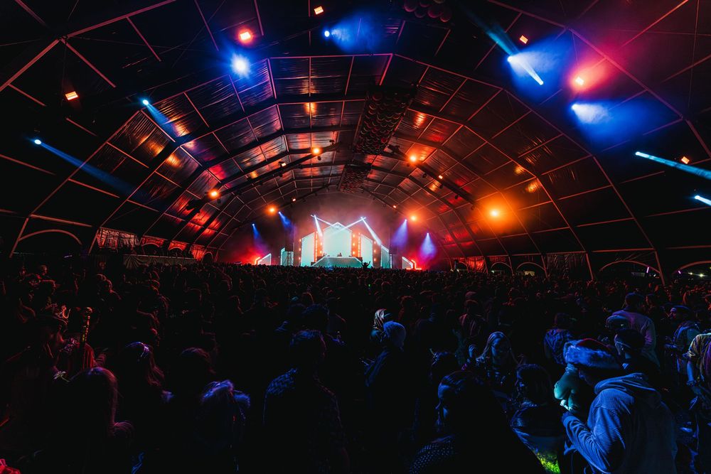 A dark nightclub interior with colorful red and blue lighting illuminating the dance floor and ceiling.