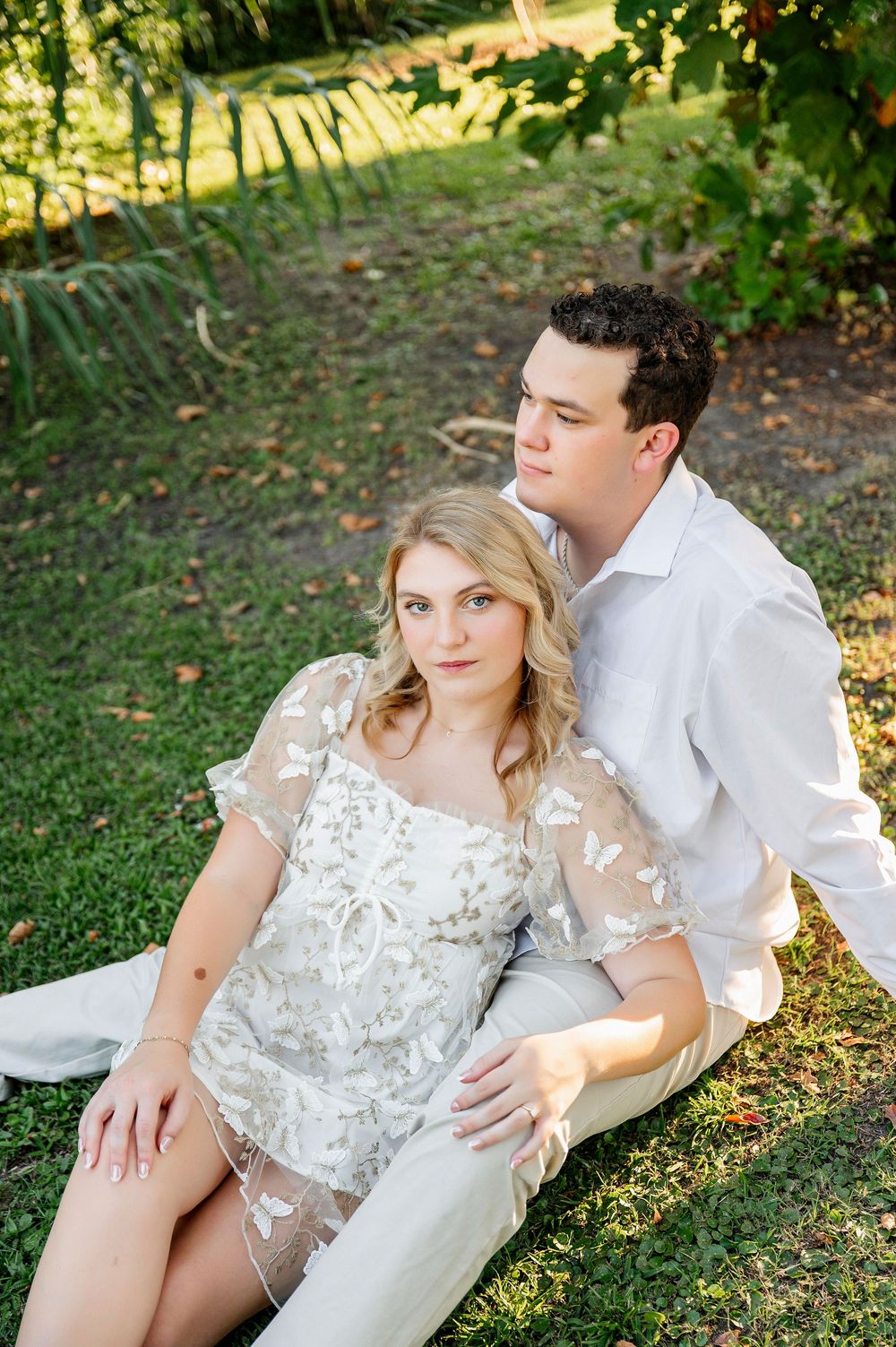 A couple poses together on grass during a romantic outdoor photoshoot.