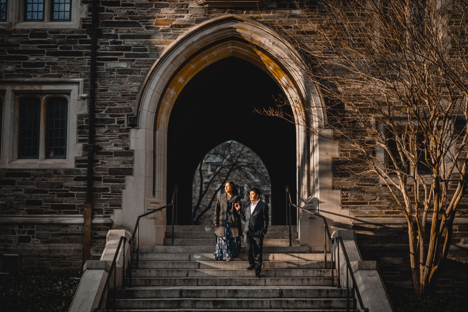 Exterior view of gothic stone church architecture with arched windows and bare winter trees.