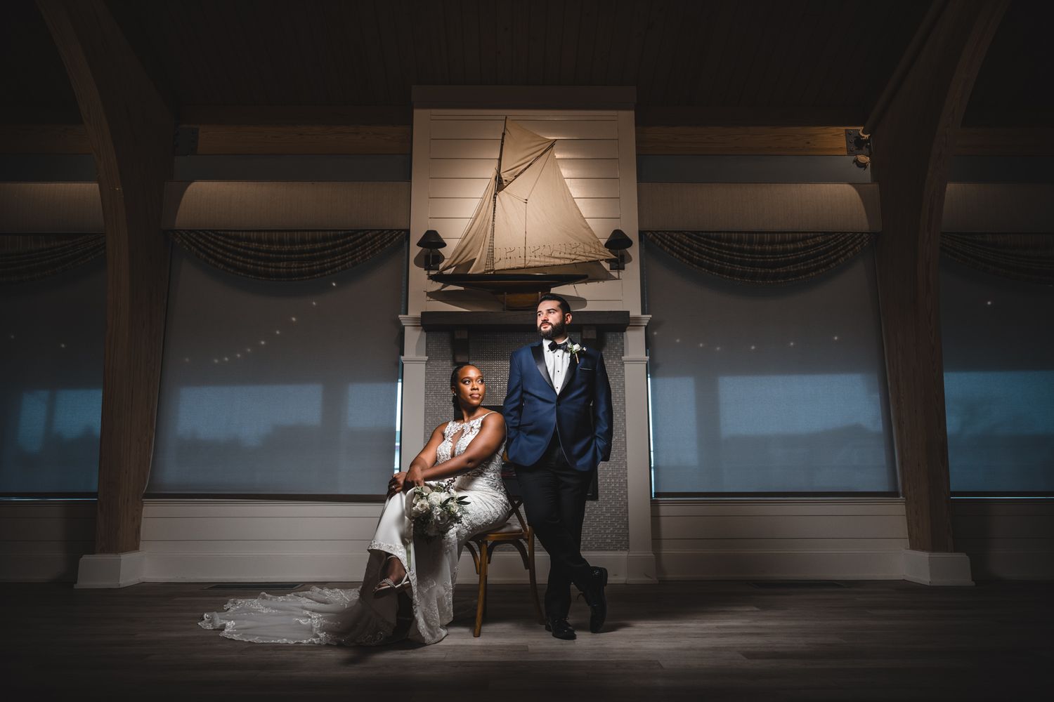 Dramatic wide shot of couple sitting in dark church interior with dramatic lighting.
