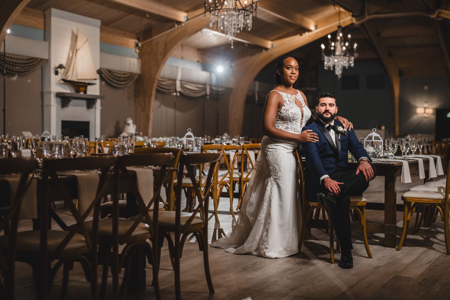 Wedding reception dance floor with guests celebrating in a rustic venue with wooden beams and chandeliers.