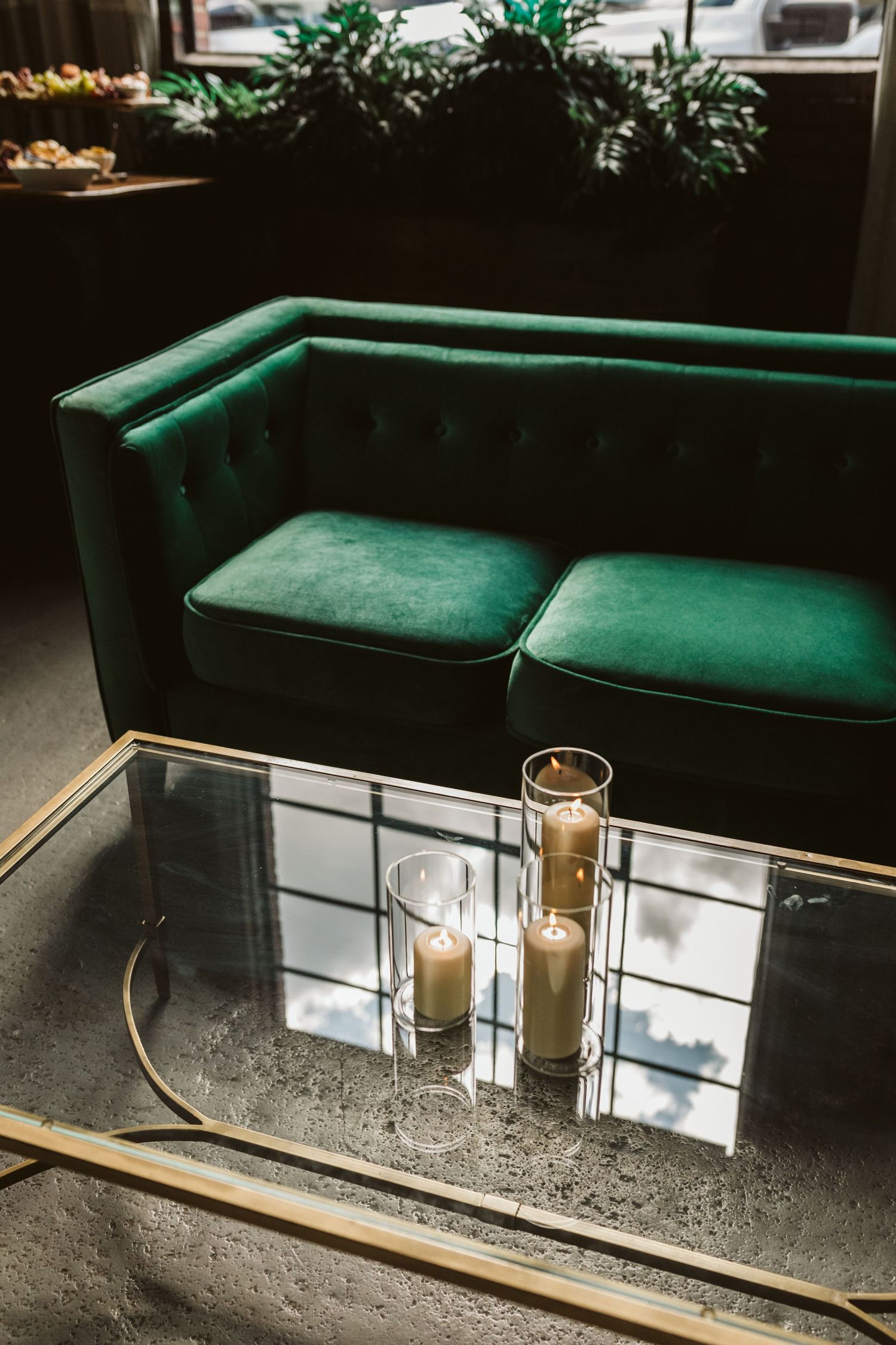 Modern bar setup with emerald green velvet seating and lit candles on a mirrored surface.
