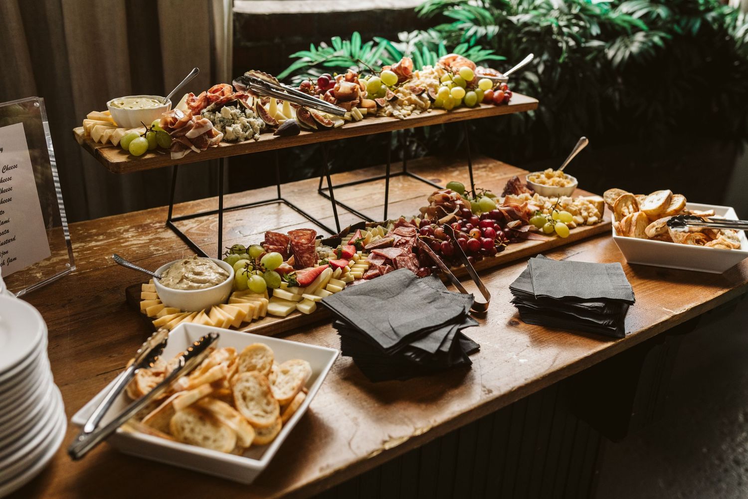 Catering display with various appetizers and charcuterie on wooden boards.
