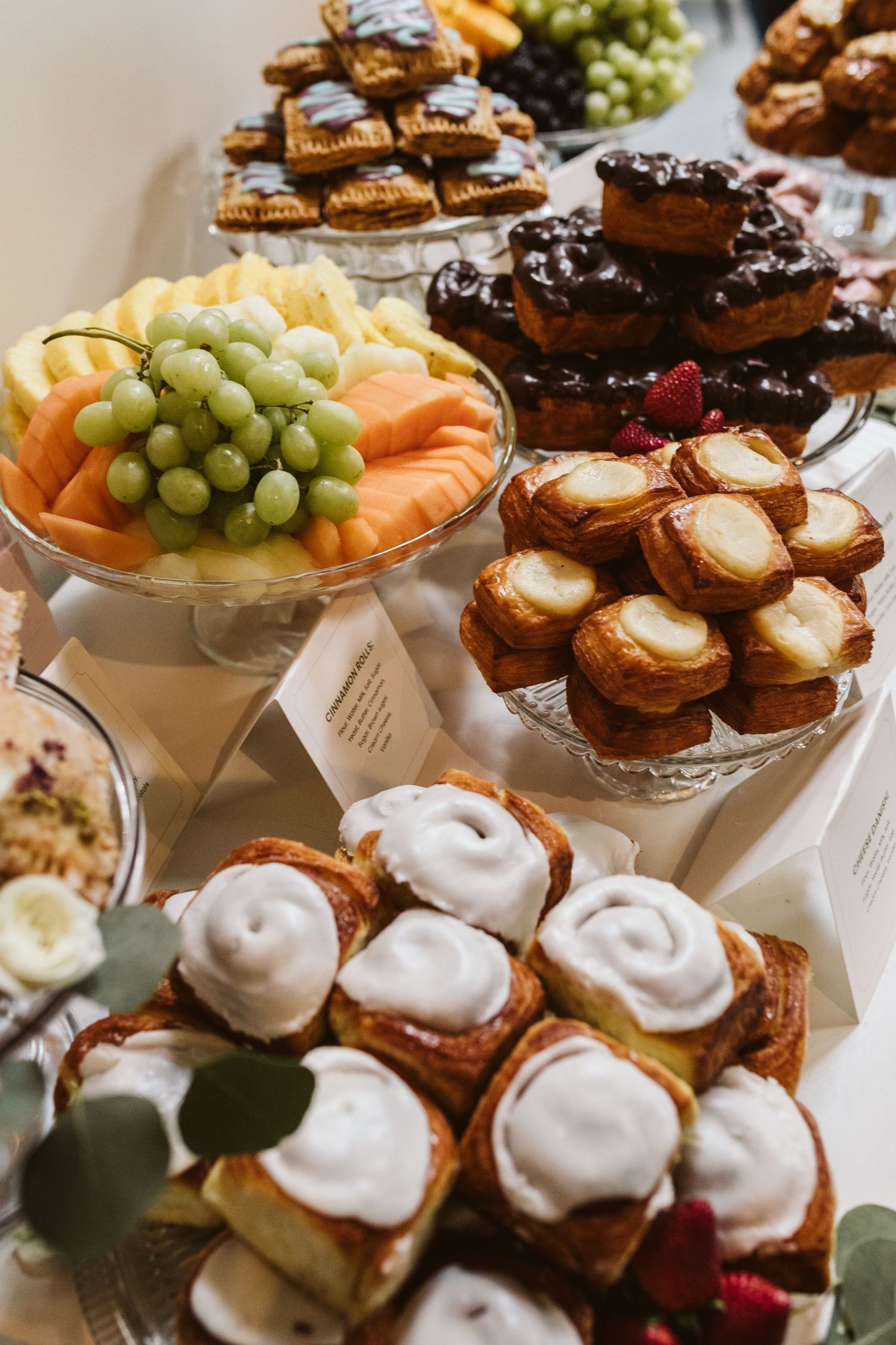 Elegant dessert display featuring frosted pastries, fresh fruit, and chocolate treats arranged on tiered serving platters.