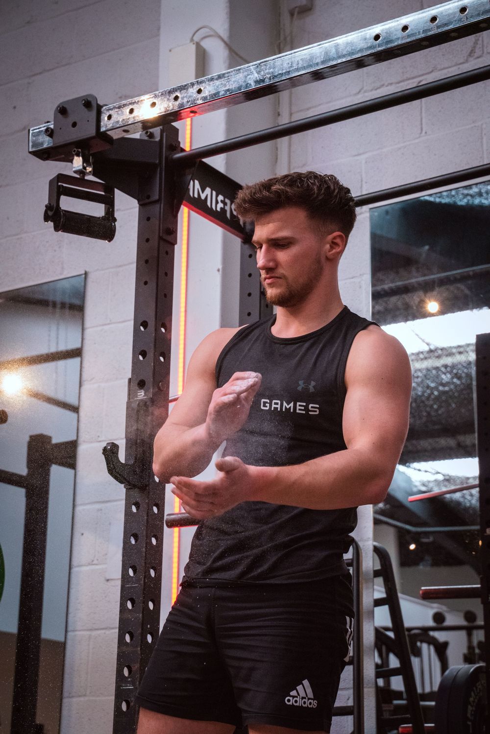 Athletic person in workout attire standing next to gym equipment in a fitness facility.