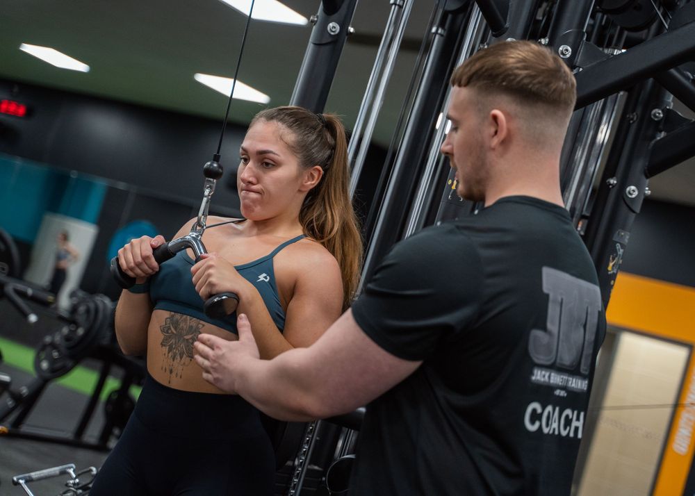 Personal training session in progress at a well-equipped modern gym facility.