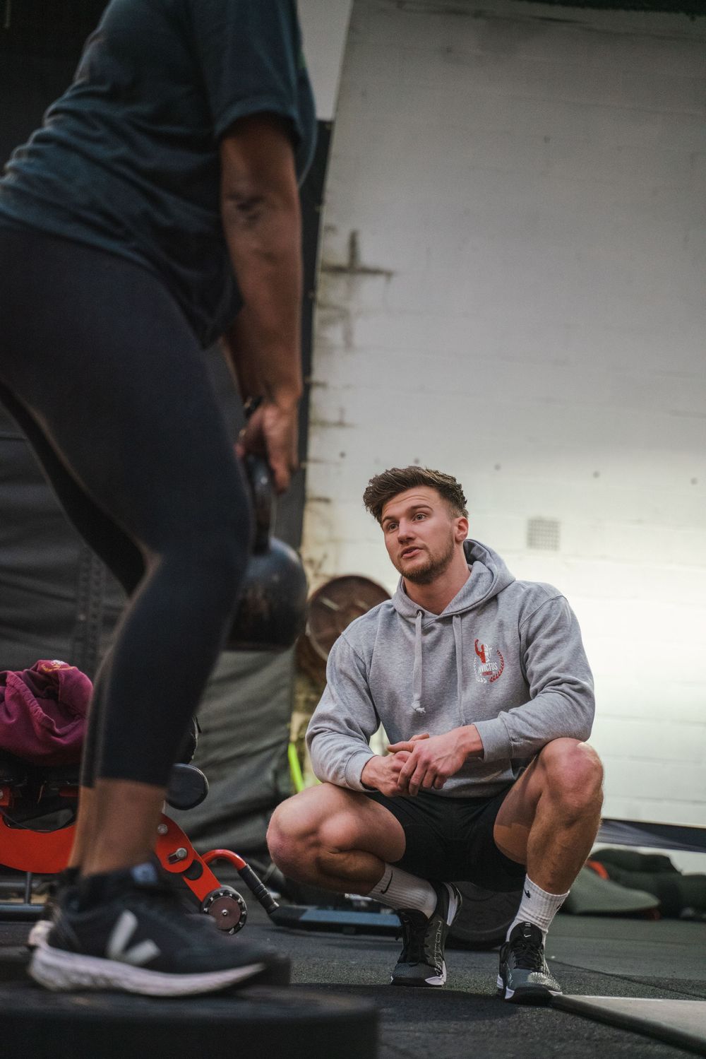 Personal trainer and client discussing workout routine in a gym environment.
