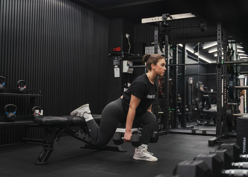 Wide angle view of modern gym equipment setup with dark walls and bright lighting.