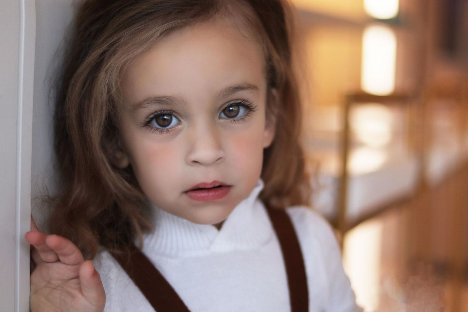 Close up portrait of 3 year old boy with long curls leaning against a white wall during Upsherin photography session in Lakewood NJ
