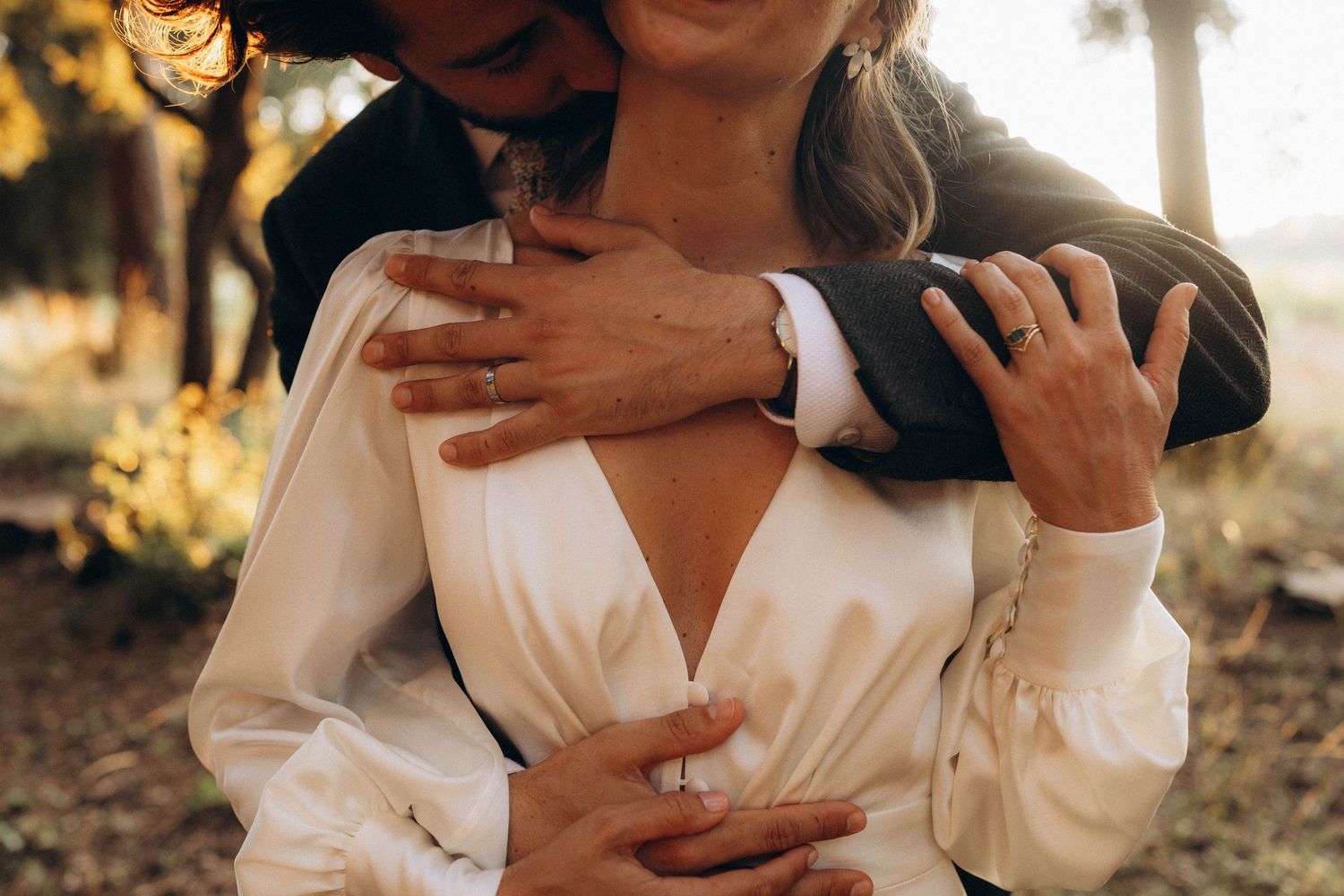 A tender embrace between newlyweds in formal attire during golden hour.