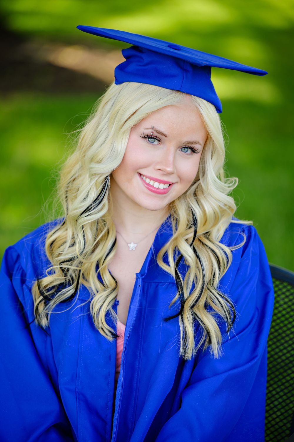 Blond haired girl wearing her cap and gown in bright blue posing for a photo before high school graduation in Columbus Ohio