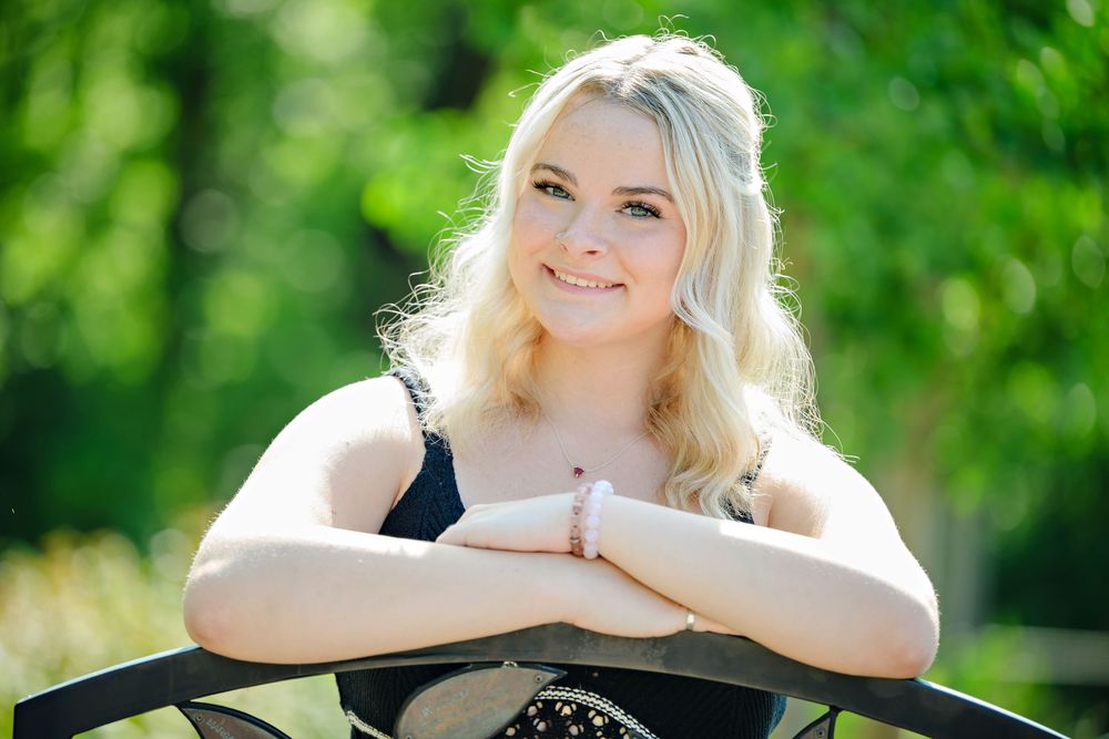 A high school senior girl poses at Inniswood Metro Garden lit from the back by the sunlight on a summer day