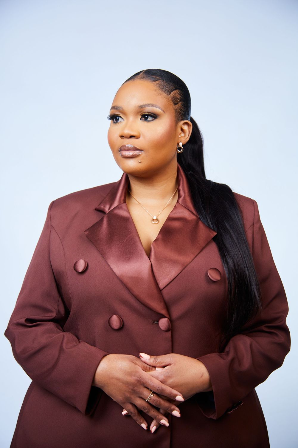 Professional portrait of person in burgundy blazer against light background.