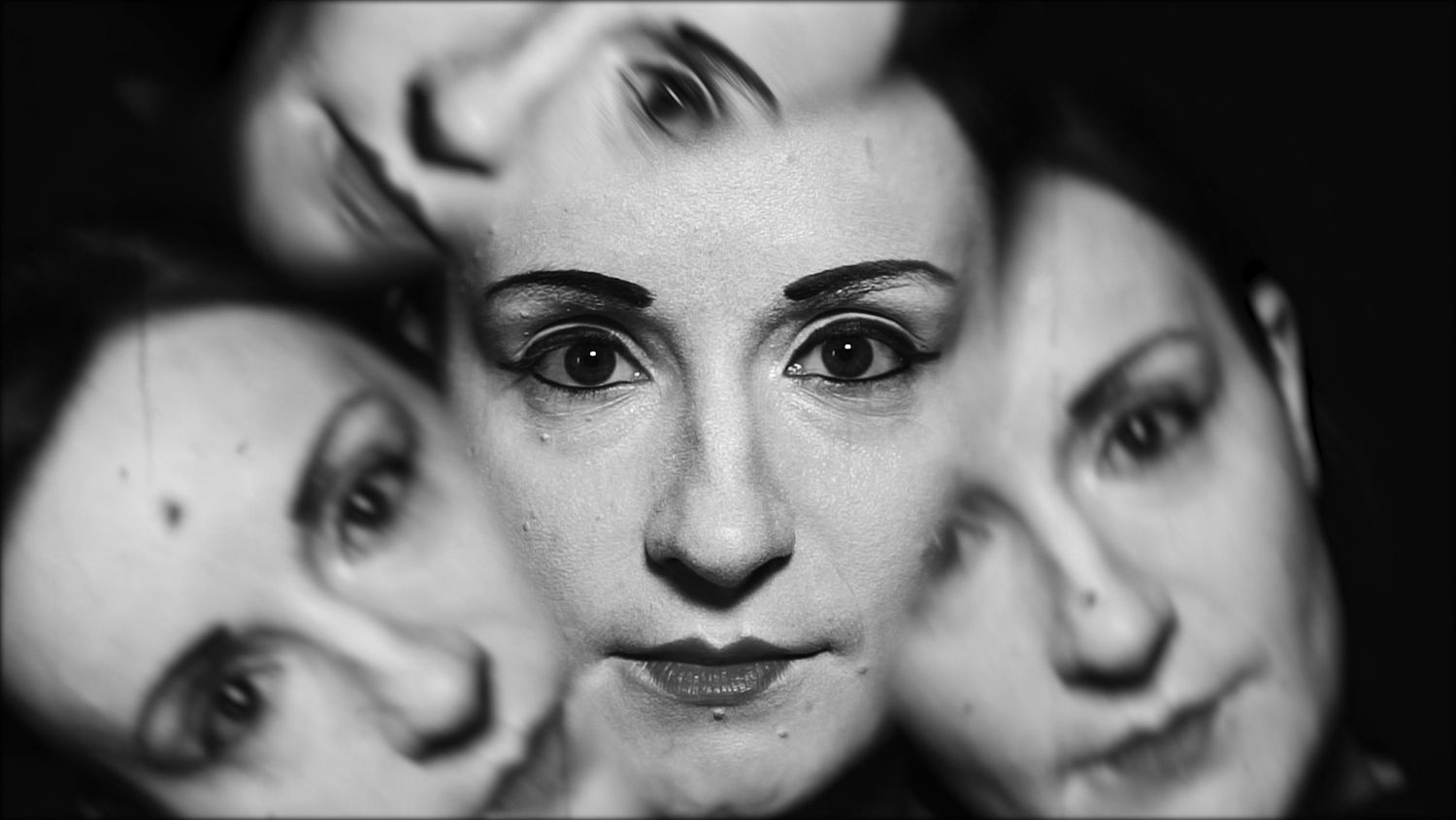 Portrait surréaliste à exposition multiple montrant trois visages superposés en noir et blanc.
