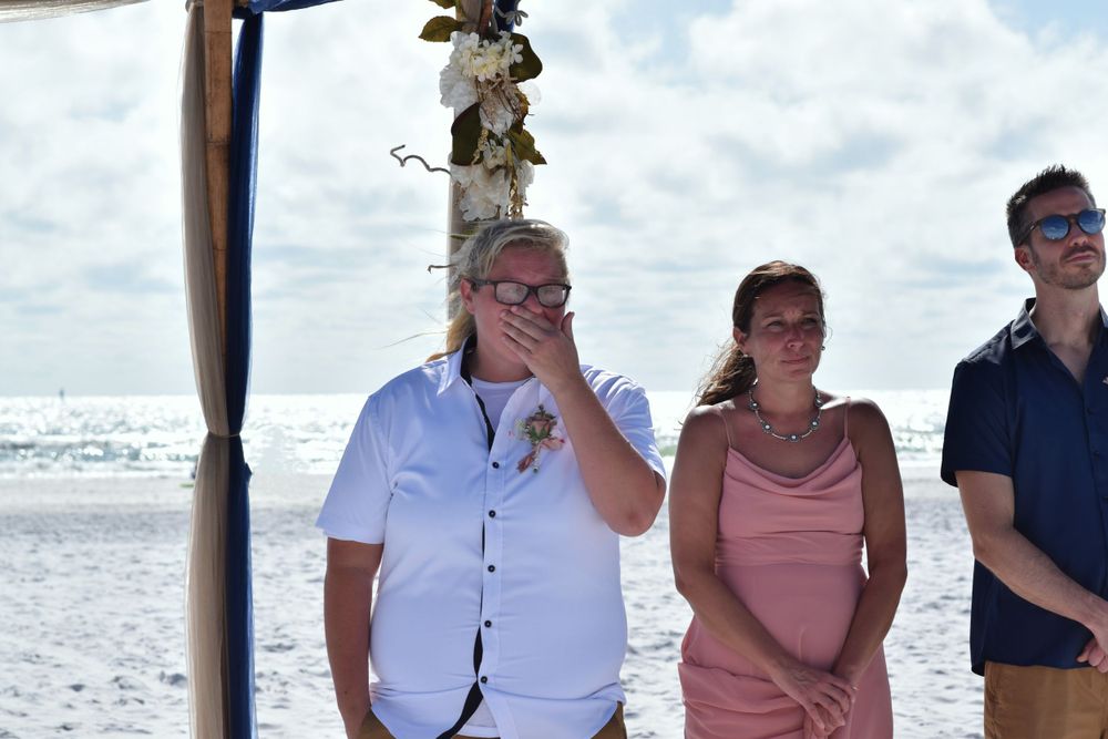 Bride emotional reaction to seeing her partner walk down the aisle on a beach captured by LMQ Photography.