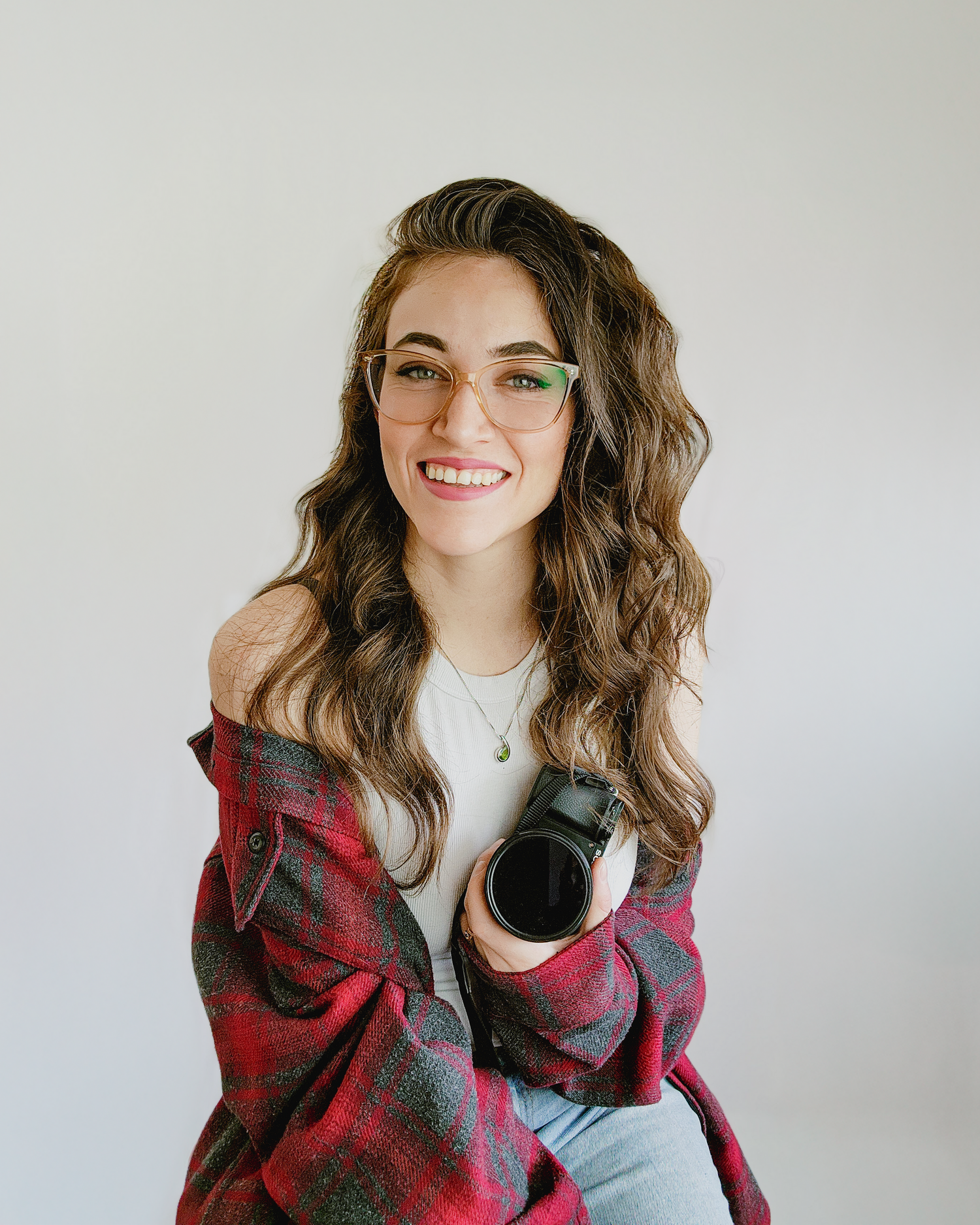 Professional headshot of someone wearing glasses and a red plaid flannel against a light background.