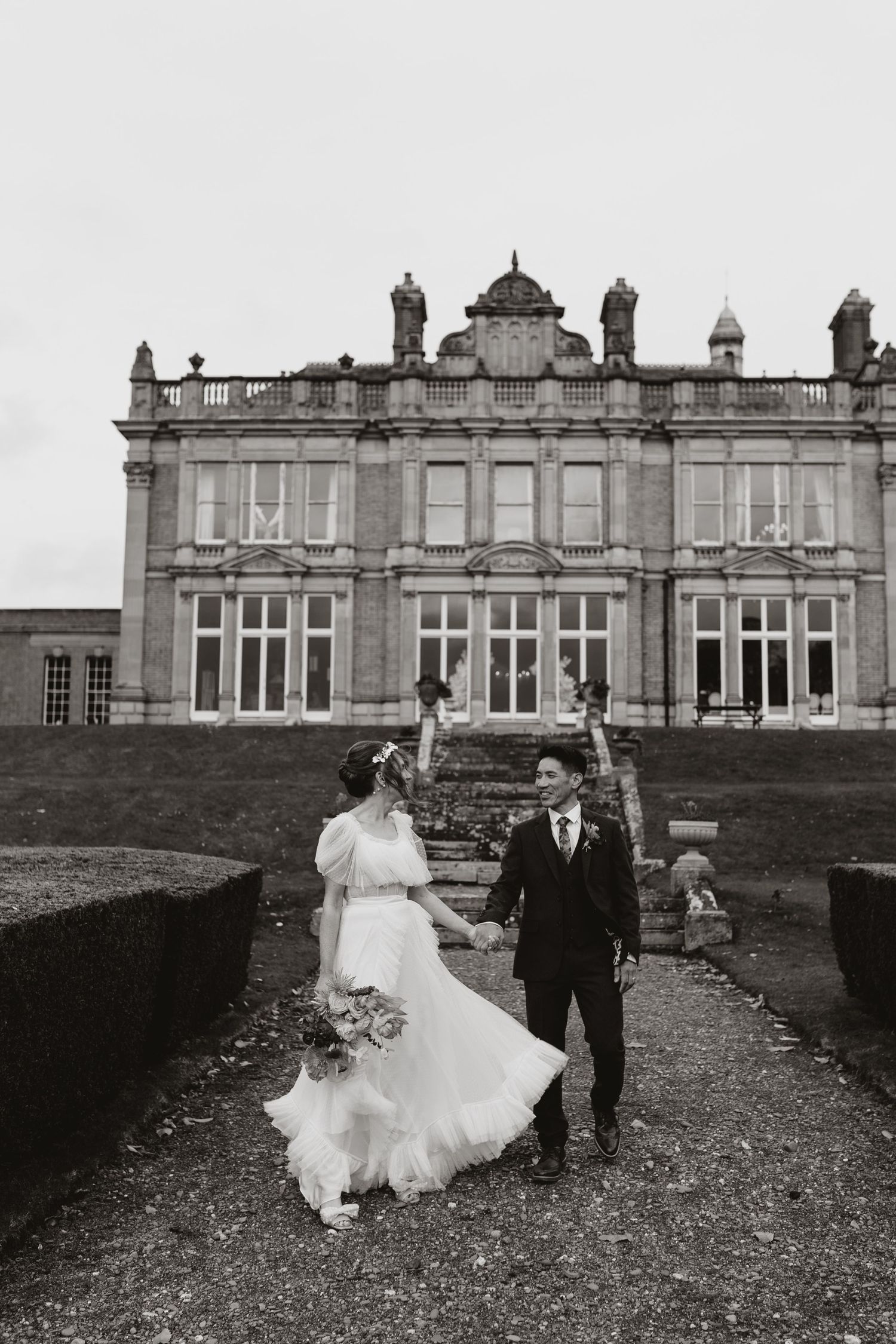 Elegant historic manor house wedding venue with ornate architecture and manicured gardens shown in black and white.