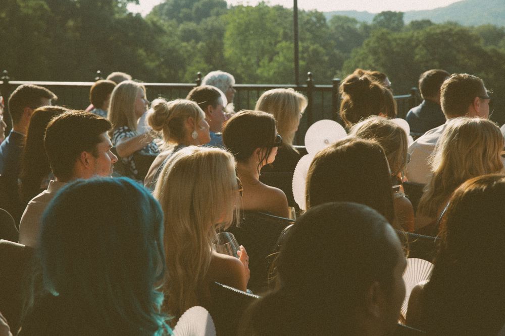 Wedding guests gather outdoors during sunset ceremony with mountain views.