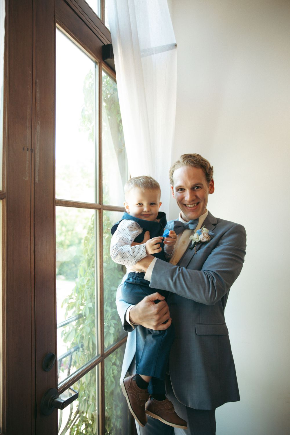 Wedding day portrait by window in elegant blue suit.
