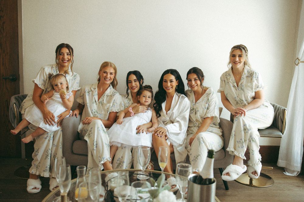 Wedding party in matching white robes relaxes together during pre-ceremony preparations.