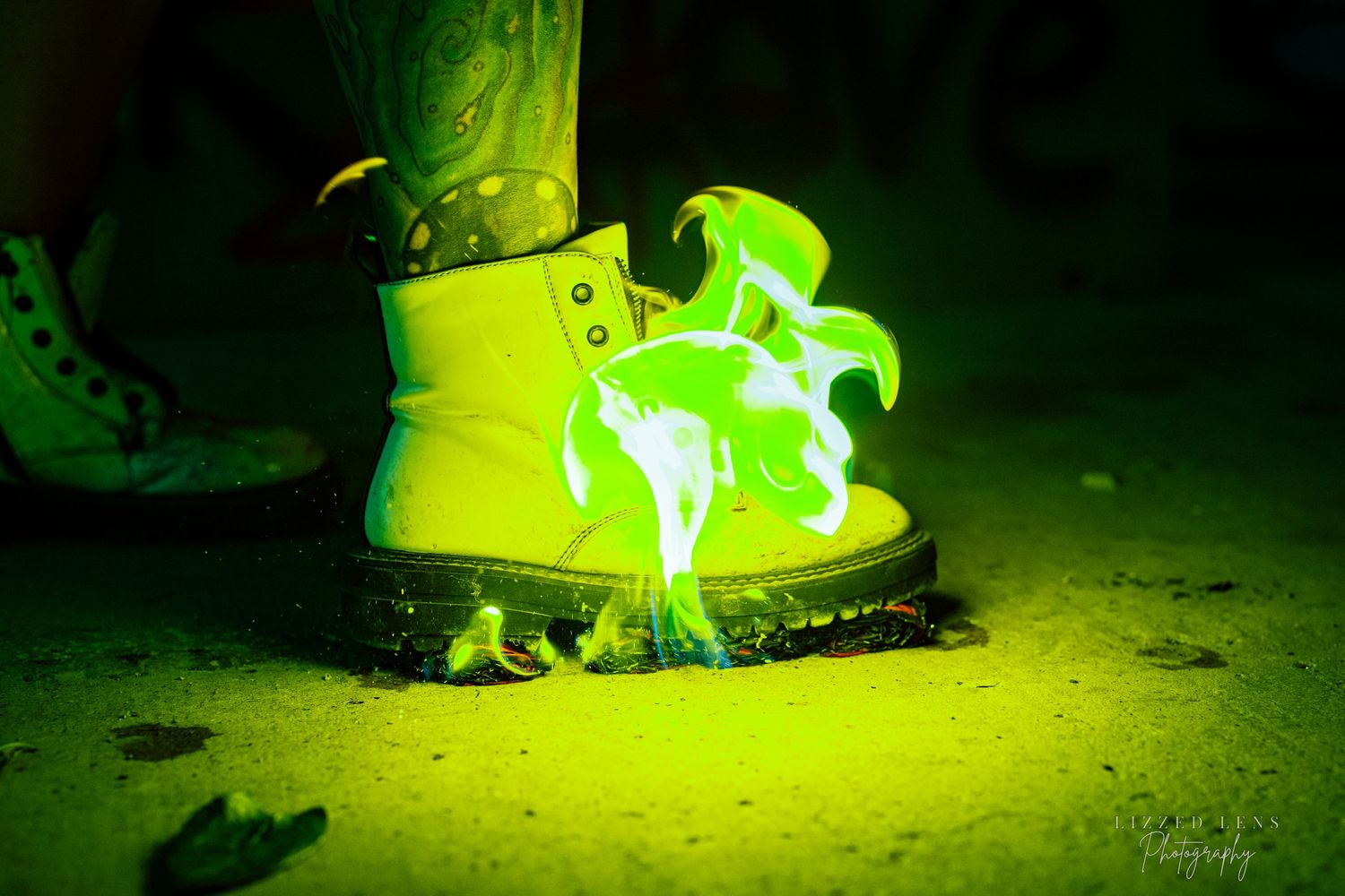 A glowing green neon light illuminates a Dr. Martens boot on a dark ground.