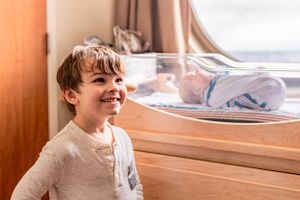Cheerful child smiles brightly near window in natural indoor lighting.