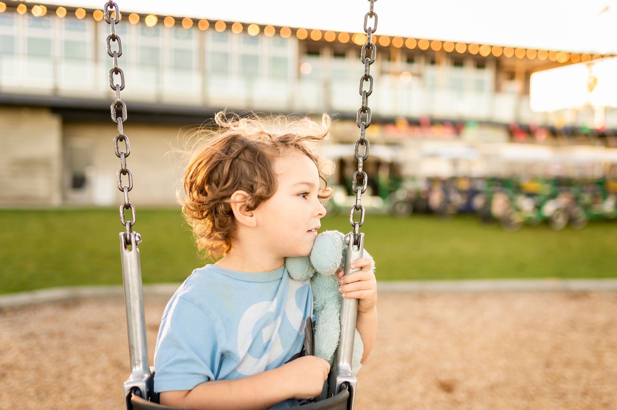 Child enjoys swinging at playground during golden hour.