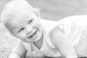 A black and white portrait shows a joyful smile on a light background.