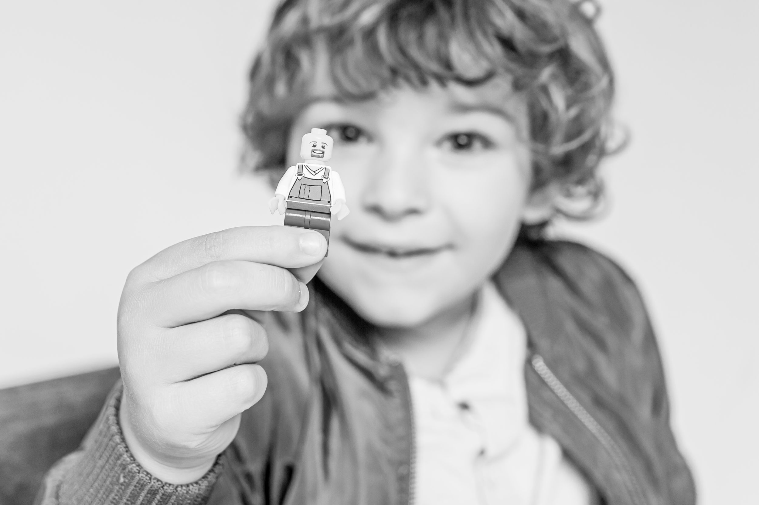 Close-up portrait holding up a small toy or figurine against a light background.