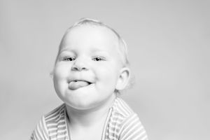 Black and white close-up portrait showing a bright smile against a plain background.