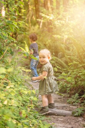 Two young people explore wooded trail in warm evening sunlight.