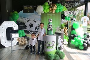 Soccer-themed birthday party display with green and white balloon decorations and sports-themed cake.